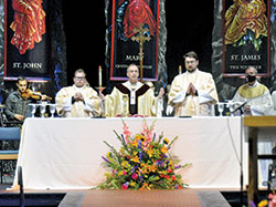 Deacons Matthew Perronie, left, and Michael Clawson, third from left, assist Archbishop Charles C. Thompson during the closing Mass at the National Catholic Youth Conference in Lucas Oil Stadium in Indianapolis on Nov. 20. (Photo by Natalie Hoefer)