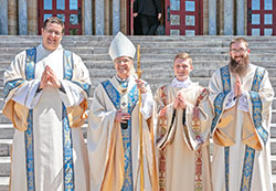 Archbishop Charles C. Thompson poses outside of the Archabbey Church of Our Lady of Einsiedeln in St. Meinrad with transitional deacons Anthony Armbruster, left, Samuel Rosko and Bobby Vogel after an April 15 liturgy in which the three archdiocesan seminarians were ordained to the diaconate. They are expected to be ordained priests for the Church in central and southern Indiana in June 2024. (Photo courtesy of Saint Meinrad Archabbey)