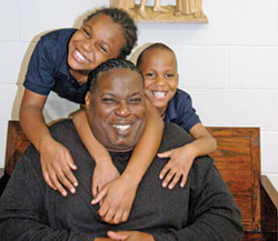 Darren Highbaugh basks in the love of his children, 9-year-old Daranasia and 6-year-old Darren Jr. at Holy Family Shelter in Indianapolis. (Photo by John Shaughnessy)