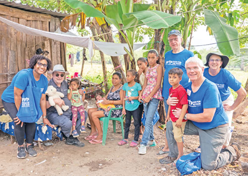 Tom Ricke, far right and kneeling, joined other members of a mission team from St. Mary Parish in Greensburg and the Food for the Poor organization who are working to bring hope and housing to families in a poor community in Honduras. Other St. Mary team members in the photo are Linda Weigel, behind Ricke, and retired archdiocesan priest, Father Carlton Beever, next to Weigel. Representing Food for the Poor are Kitty Soriano, left, and Father Bob White, holding a stuffed bear. (Submitted photo)