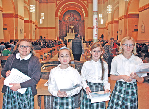 Before the archdiocese’s Catholic Schools Week Mass at SS. Peter and Paul Cathedral in Indianapolis on Jan. 29, a group of sixth-grade students handed out worship aids to participants. Leanna Paul, left, of St. Gabriel School in Connersville joined three students from St. Mary School in Rushville: Maria Mosburg, left, Hadley Burklow and Kallie Gettinger. (Photo by John Shaughnessy)
