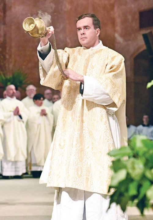 Transitional Deacon Thomas Day incenses concelebrating priests on April 15 at SS. Peter and Paul Cathedral in Indianapolis during the annual archdiocesan chrism Mass. Deacon Day will be ordained a priest on June 7 at the cathedral. (Photo by Sean Gallagher)