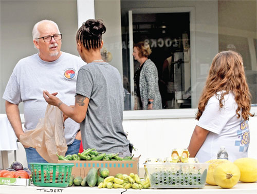 Tony Talbert speaks with a woman at a free vegetable table outside David’s House, the ministry building of the Society of St. Vincent de Paul Tri-County Good Samaritan conference, in Richmond on Sept. 10, 2023. (Photo by Natalie Hoefer)