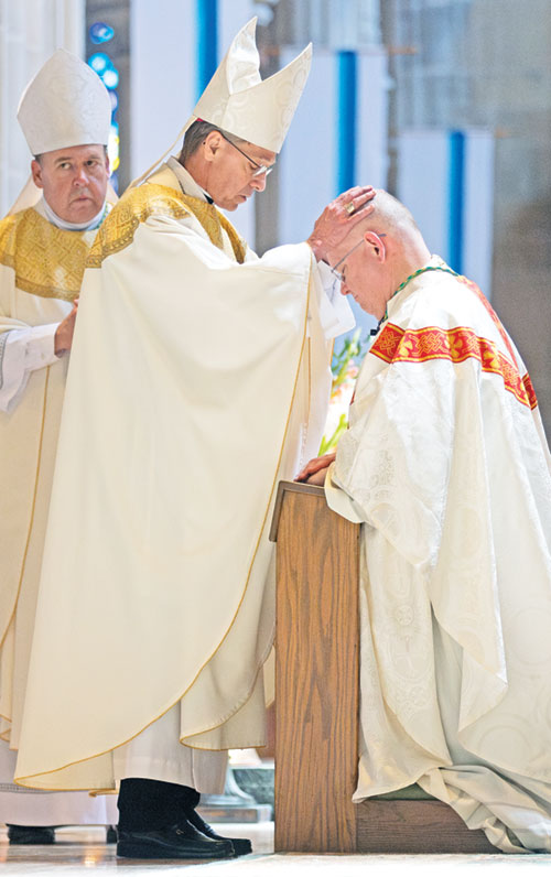 Archbishop Charles C. Thompson ritually lays hands on Bishop-designate Godfrey Mullen on May 1 in the Cathedral of St. Peter in Belleville, Ill., during a Mass in which Bishop-designate Mullen was ordained and installed as the 10th bishop of the Diocese of Belleville. He was previously a monk of Saint Meinrad Archabbey in St. Meinrad. (Photo courtesy of Saint Meinrad Archabbey)