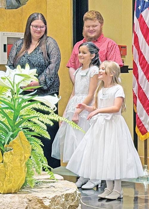 Eisley Smith, right, smiles with joy as she prepares to be baptized during the Easter Vigil Mass at Most Sacred Heart of Jesus Church in Jeffersonville on April 4. The 8-year-old girl felt called to become Catholic after learning about the faith at Sacred Heart School in Jeffersonville. (Submitted photo)