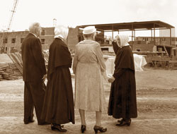 In this file photo published in The Criterion on Aug. 19, 1966, Mother Marie Mathilde, far right, superior of the Little Sisters of the Poor in Indianapolis, shows her assistant and two guests how much progress has been made on construction of the new St. Augustine Home for the Aged at 2345 W. 86th St. The home was built with donations from more than 18,000 individuals, families, 
        businesses and foundations.