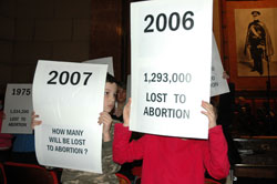 Lucas Jirgal, left, and his sister, Anna, standing behind her sign, hold posters that show the number of babies who died in abortions in 2006 and question how many will die this year. They participated in the Right to Life of Indianapolis Memorial Service for the Unborn on Jan. 28 in Indianapolis. They are members of St. Elizabeth Ann Seton Parish in Carmel, Ind., in the Lafayette Diocese.