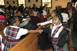 Holy Angels School first-graders Kumba Songor, left, and Karrington Abstone of Indianapolis shake hands during the Sign of Peace on Jan. 12 at Holy Angels Church as part of a memorial Mass honoring the life and ministry of Dr. Martin Luther King Jr. St. Anthony School students also participated in the march and Mass as part of their classroom lessons about the Civil Rights Movement during the 1960s. (Photo by Mary Ann Wyand) 