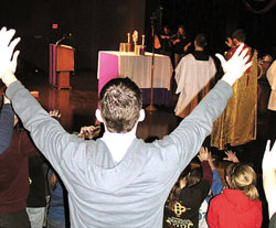 A participant at the March 3-4 Archdiocesan Youth Rally held at Our Lady of Providence Jr./Sr. High School in Clarksville raises his hands in prayer while joining others in eucharistic adoration.