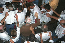 Men lay hands on each other at a Christ Renews His Parish weekend retreat at St. Barnabas Parish in Indianapolis. Christ Renews His Parish is a nearly 40-year-old parish renewal process where separate groups of men and women participate in weekend retreats that are facilitated by other men or women of the parish.