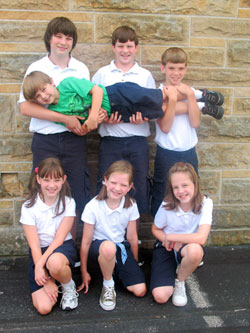 Adding their own unusual flair to the school year, all seven children of Jim and Kitty Madden are attending St. Roch School in Indianapolis. From left, Kathryn, Kimberly and Anna take a knee for the team while, from left, Sam, Mike and Jack lift Joe to new heights.	(Submitted	photo)	
