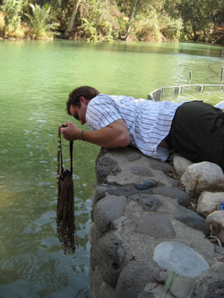 Adam Boyden dips his rosaries into the Jordan River, the site of Jesus’ baptism. Many young adults placed objects into the river to take back for family and friends. 