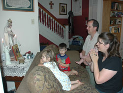 Our Lady of Lourdes parishioners Gary and Jennifer Lindberg of Indianapolis pray with their children, 2-year-old Clare, 4-year-old Alex and 6-month-old Jonas, every day in their home. They look forward to Sunday as a day of rest and relaxation.