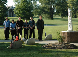 Father Steven Schwab, third from left, pastor of St. Thomas Aquinas Parish in Indianapolis and Catholic chaplain of the Indianapolis Metropolitan Police Department, prays with emergency medical technicians, firefighters, police officers and military personnel during the playing of “Taps” at the fifth annual archdiocesan Blue Mass on Sept. 11 at Calvary Cemetery in Indianapolis.