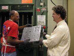 Instead of throwing away old computers, some Catholic schools and parishes in the archdiocese have turned to RecycleForce, an Indianapolis company that recycles parts from old electronic equipment and employs people just released from prison to do the work. Here, employee John Hill takes a computer shell from the company’s president, Thomas Gray.