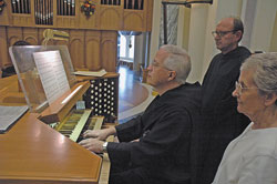 Benedictine Father Harry Hagan and Providence Sister Regina Marie McIntyre look on as Benedictine Father Prior Tobias Colgan plays the tune he composed for the hymn text in honor of St. Theodora Guérin written by Father Harry. Father Tobias played the tune on Oct. 3, St. Theodora’s feast day, on the organ of the Archabbey Church of Saint Meinrad Archabbey in St. Meinrad, where he and Father Harry are members.