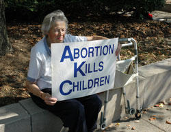 St. Andrew the Apostle parishioner Mary Jane Dye of Indianapolis sits in the shade during the Central Indiana Life Chain on Oct. 7 in Indianapolis. Temperatures climbed to 90 degrees on Respect Life Sunday. She and her husband, John, participate in the one-hour Life Chain prayer vigil every year.