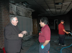 Father John Beitans, pastor of St. Lawrence Parish in Indianapolis, talks with Tony Camacho, a supervisor with ServiceMaster, on Nov. 4 about clean-up work under way in the St. Lawrence Church narthex after a late-night fire on All Souls Day caused by votive candles that melted and burned out of control.