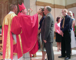 Archbishop Daniel M. Buechlein anoints Cassie Caccavo while her sponsor, Jim Clark, stands by her during the sacrament of confirmation at SS. Peter and Paul Cathedral in Indianapolis. Cassie and Clark are members of St. Simon the Apostle Parish in Indianapolis. (Submitted photo) 