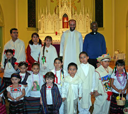 Father Todd Goodson, fourth from left in the back row, poses with children wearing traditional costumes after a Dec. 12 Mass in honor of Our Lady of Guadalupe celebrated at St. Ambrose Church in Seymour. Standing to his left is Father Kenneth Taylor, director of the archdiocesan Office of Multicultural Ministry. (Submitted photo) 