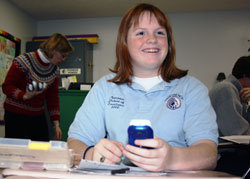 Alyssa Hendershot, a sophomore at Our Lady of Providence Jr./Sr. High School in Clarksville, holds a wireless device commonly known as a clicker that allows her to interact with classroom lectures and take tests. It is an element of SMART technology in four classrooms at Providence. Alyssa’s science teacher, Virginia Shirley, stands in the background and holds several more clickers. (Submitted photo) 