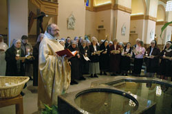Benedictine Father Julian Peters, administrator pro-tem of SS. Peter and Paul Cathedral Parish in Indianapolis, blesses candles at the start of the World Day for Consecrated Life Mass on Feb. 2 in the cathedral. Joining him in the blessing are members of religious communities ministering in the archdiocese. (Photo by Sean Gallagher)	