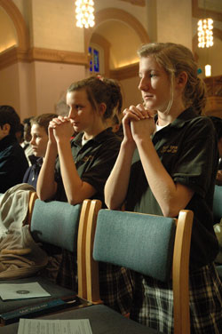 From left, Dominic Spears, a seventh-grader at Holy Spirit School in Indianapolis, and Shelby Hughbanks and Katie Oskay, both eight-graders at Holy Spirit School, kneel in prayer on Jan. 30 at SS. Peter and Paul Cathedral in Indianapolis during a Mass in observance of Catholic Schools Week. (Photo by Sean Gallagher)	