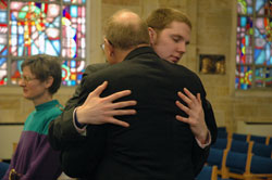 Seminarian Andrew Proctor, in his fourth year at the Bishop Bruté College Seminary at Marian College in Indianapolis, exchanges the Sign of Peace with his father, David Proctor, a member of Our Lady of the Greenwood Parish in Greenwood. (Photo by Sean Gallagher)	