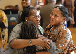 Holy Spirit parishioners Christine Kateregga, left, and her mother, Magdalene Kateregga, of Indianapolis hug Holy Angels parishioner Miranda Stovall during the sign of peace as part of the African Mass on March 2 at St. Rita Church in Indianapolis. (Photo by Mary Ann Wyand) 