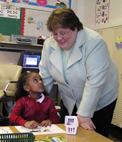 Ruth Tinsley, principal of St. Andrew & St. Rita Catholic Academy and Central Catholic School in Indianapolis, helps pre-kindergarten student Chya Jennings with her classroom work in this 2006 file photo. Both schools are part of the Mother Theodore Catholic Academies. (File photo by Sean Gallagher)