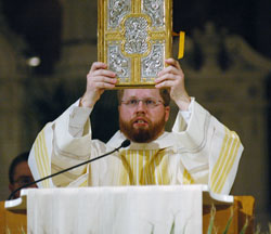 Transitional Deacon Joseph Newton holds up the book of the Gospels during the annual archdiocesan chrism Mass celebrated on March 18 at SS. Peter and Paul Cathedral in Indianapolis. (Photo by Sean Gallagher) 