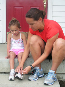 Laura Phillips, right, laces up her 3-year-old daughter Kate’s shoes as they prepare for a run around their Indianapolis neighborhood. (Photo by John Shaughnessy)