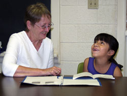 In this file photo, Holy Trinity parishioner Barbara Pierse of Edinburgh helps Lilia Perez improve her English language skills during a class at the parish in 2004. A key part of evangelization is seeing the presence of God in others and acting in a loving way toward them. (File photo by Mary Ann Wyand)