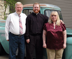Deacon Joseph Newton poses for a picture with his parents, Our Lady of the Greenwood parishioners Larry and Caroline Newton of Greenwood, on May 22 in front of his 1956 Chevrolet pick-up truck, which he is restoring as a hobby. Deacon Newton’s brother, Tommy, and his wife, Ashley, and their children, Joseph and Seth, will sit with his sister, Jessica Fulp, and her husband, Mike, during the ordination Mass on June 7 at SS. Peter and Paul Cathedral. (Photo by Mary Ann Wyand)