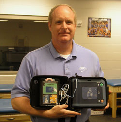 Bishop Chatard High School athletic director Mike Ford shows the Automated Electronic Defibrillator that was donated to the Indianapolis North Deanery high school by the Reviving Hearts Program. The program hopes to have the life-saving medical device at all Indiana high schools within five years. (Photo by John Shaughnessy)