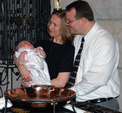 Angela and Daniel Sarell hold their 8-week-old daughter, Allana Hope, during her baptism on June 1 at St. Luke the Evangelist Church in Indianapolis. Father Stephen Giannini, then pastor of St. Luke Parish, presided at the liturgy. (Submitted photo) 