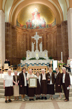 Carmelite sisters of the former Monastery of the Resurrection in Indianapolis pose with a proclamation from Archbishop Daniel M. Buechlein after a Mass of Thanksgiving on July 16 at SS. Peter and Paul Cathedral. They are, from left, Sisters Marcia Malone, Rachel Salute, Ruth Boyle, Jean Alice McGoff, Rita Howard, Anna Mary Larkin, Helen Wang, Elizabeth Meluch and Teresa Boersig. (Photo courtesy Denis Ryan Kelly Jr.) 