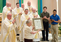 Carmelite Sister Jean Alice McGoff, prioress of the Indianapolis Carmel, displays a proclamation from Archbishop Daniel M. Buechlein at the conclusion of Mass on July 16 at the cathedral. Msgr. Joseph F. Schaedel, vicar general, left, presented the award on behalf of Archbishop Buechlein. Diocesan and order priests join archdiocesan seminarians Andrew Cope, second from right, and Martin Rodriguez, right, in showing their thanks to the nine Carmelite sisters who moved to Oldenburg on June 30. (Photo courtesy Denis Ryan Kelly Jr.) 