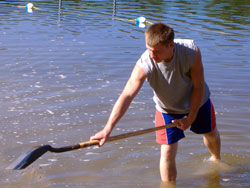 Bryce Denning, a member of St. Meinrad Parish in St. Meinrad, helps reclaim a beach on a pond in an interdenominational center for troubled youths in Michigan while participating in “Service Week.” The mission trip was sponsored by St. Robert of Newminster Parish in Ada, Mich., and brought in nearly 150 youths from several dioceses during late July. (Submitted photo) 