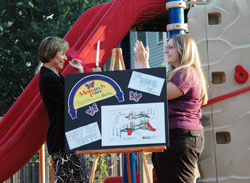 St. Joan of Arc School principal Mary Pat Sharpe of Indianapolis, left, cuts the ribbon on new playground equipment with help from Suzi Abell, right, director of curriculum and the art teacher, during a Sept. 22 dedication ceremony at the Indianapolis North Deanery parish. The school’s Monarch Parc was dedicated in Sharpe’s honor for six years of exceptional service to the students. (Photo by Mary Ann Wyand) 