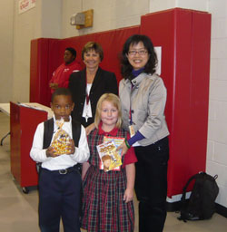 St. Joan of Arc School students Jalen Love, left, and Marianne Gaebler come bearing gifts for Liu Shu-Chen, right, a principal from Taiwan who visited the north-side Indianapolis school on Oct. 14-15. St. Joan of Arc principal Mary Pat Sharpe also welcomes Liu. Liu’s visit to St. Joan of Arc School was arranged by the Indiana Department of Education as part of its international exchange project to build friendship and cooperation between schools in Indiana and Taiwan. (Submitted photo) 