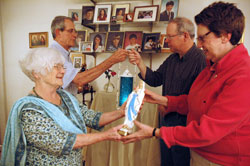 St. Michael the Archangel parishioners Peggy and Bob Geis, left, present a blessed Marian statue and vigil light to parishioners Phil and Patricia Price, all of Indianapolis, on Oct. 13 in the Geis home after a group rosary there. Twenty-nine parishioners hosted the Marian devotion in their homes throughout the month of October. (Photo by Mary Ann Wyand) 