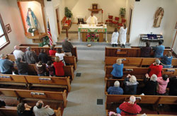 Members of Holy Rosary Parish in Seelyville kneel in prayer while Father Dominic Chukwudi, administrator, prays the eucharistic prayer during a Nov. 9 Mass at the parish’s church. Archbishop Daniel M. Buechlein was the primary celebrant of an Oct. 11 Mass at the parish that celebrated the 100th anniversary of its founding. (Photo by Sean Gallagher) 