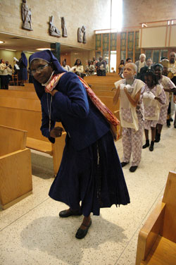 Daughters of Mary Mother of Mercy Sister Jennifer Otuonye, a native of Nigeria who ministers in Indianapolis, carries the Book of Gospels inside a cloth knapsack to the altar in a ceremonial dance during the fifth annual archdiocesan African Catholic Mass on Dec. 7 at St. Rita Church in Indianapolis. (Photo by Mary Ann Wyand) 