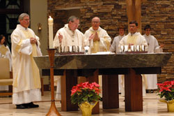 Archbishop Daniel M. Buechlein celebrates the Mass of Dedication for the new St. Malachy Church in Brownsburg on Dec. 16 as Msgr. Joseph F. Schaedel, vicar general, center, and Father Daniel Staublin, pastor, right, assist as concelebrants. Deacon Daniel Collier stands at the left of the altar. Jason Kippenbrock, back left, and Scott Kelley were among the altar servers. Priests with connections to St. Malachy Parish and pastors of other Indianapolis West Deanery parishes also concelebrated the historic Mass. (Photo by Mary Ann Wyand) 