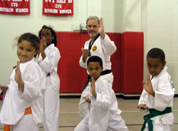 Students at St. Joan of Arc School in Indianapolis follow the lead of Father Guy Roberts to demonstrate a tae kwon do move during an after-school program. Lauren Graves, from left, Aleise Holder, Micah Jackson and David House are among the 30 students who meet twice a week for lessons from Father Roberts, the pastor of St. Joan of Arc Parish, who has earned a black belt in tae kwon do. (Photo by John Shaughnessy) 