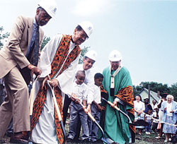 Archbishop Daniel M. Buechlein breaks ground for the new Holy Angels School and Parish Center in Indianapolis with help from Father Clarence Waldon, then-Mayor Steve Goldsmith, students and others involved in the project. The new school opened on Aug. 30, 1999. It was the first new inner-city school built in the United States in 40 years and was made possible by the archdiocesan Making a Difference campaign. (Archive photo) 