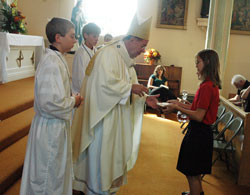 Archbishop Daniel M. Buechlein receives offertory gifts on Sept. 7, 2008, at St. Paul Church in New Alsace from Ryley Stonebreaker, a sixth-grader at the parish school, and (not seen) Gabby Meyer, a fifth-grader at the school, during a Mass that celebrated the 175th anniversary of the founding of St. Paul Parish. Assisting Archbishop Buechlein are altar servers Matthew Horner, left, and Andy Galle, both former St. Paul School students. This year, St. Paul School is starting its 175th consecutive year in operation. (File photo by Sean Gallagher) 