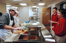 Volunteer David Marsee, left, serves lunch on Jan. 7 at Seton Catholic High School to seventh-grader Rhett Butler, left, a member of St. Mary Parish in Richmond, and Drew Barrett, a member of St. Andrew Parish in Richmond. Marsee, a parent of a student at Seton Catholic High School, is assisted by volunteer Evelyn Miller, also a parent of a student at the school. (Photo by Sean Gallagher) 