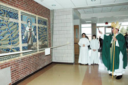 Archbishop Daniel M. Buechlein blesses a tile mosaic of St. Lawrence on Feb. 15 in the new entrance of Father Conen Hall at St. Lawrence Parish as part of his pastoral visit to the Indianapolis North Deanery parish. St. Lawrence School art teacher Allison Altherr, project volunteer Anna Marie Burrell and other parishioners helped the students with the project. Archbishop Buechlein was also the main celebrant at a Mass before the blessing ceremony. (Photos by Mary Ann Wyand) 